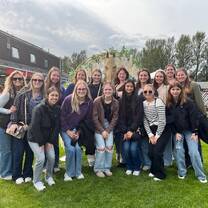 Group of students smiling and standing together with horses on a Scottish farm during the equine summer study program.