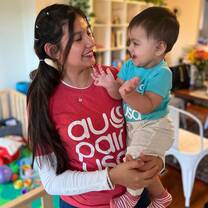 Au pair smiles at baby while holding him