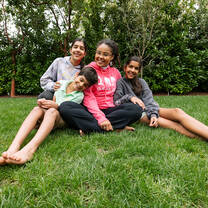 Au pair sitting on lawn with three host children