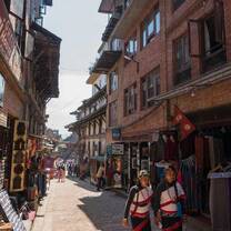 A traditional street scene in Kathmandu with local shops and two people in traditional attire.