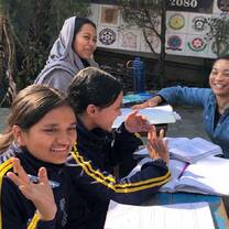 Interns and students smiling while studying outdoors at a school in Kathmandu, Nepal.