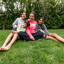 Au pair sitting on lawn with three host children