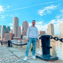Young man standing on pier with city skyline in the background