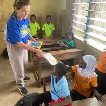 Volunteer handing book to student