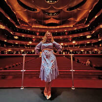 Young woman posing on stage with an empty theater in the background