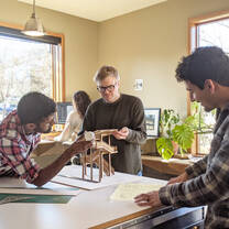 Three male engineering interns creating a wooden model