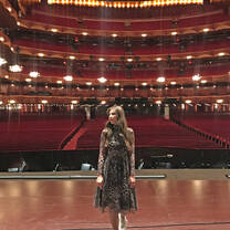 Young woman posing on stage with an empty theater in the background