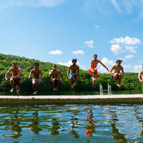 Camp USA participant jumping from a pier