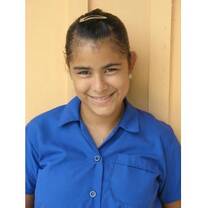 A young girl from Belize smiles in her school uniform.