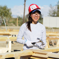 Volunteer stops to smile for camera, mid-hammer