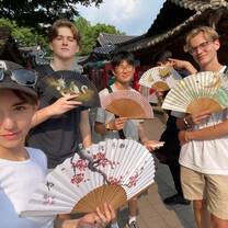 Students holding out fans near temple in South Korea