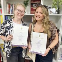 Two graduates with certificates