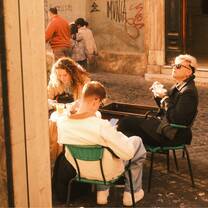 Three EF Gap Year students sitting outdoors at a café in Rome, enjoying espresso and juice while surrounded by cobblestone streets and local culture.