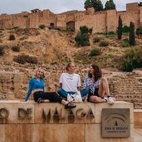 EF Gap Year students sitting by the Alcazaba in Málaga, Spain, laughing and enjoying the view of the historic fortress on a warm afternoon during their Spanish adventure.
