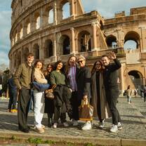A group of EF Gap Year students smiling and posing together in front of the Colosseum in Rome on a sunny day, enjoying their study abroad experience.