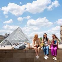EF Gap Year students hanging out by the Louvre Pyramid in Paris, laughing and soaking up the sunshine while exploring one of the world’s most iconic museums.