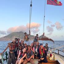 Crew on the bow of the ship with Saba in the background