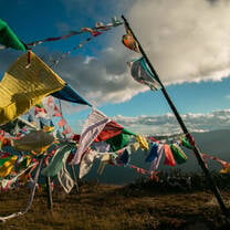 Prayer flags flying in the wind in the mountains of Bhutan with large clouds above in a light blue sky
