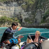 Two divers sitting on the boat during a surface interval with a cliff in the background