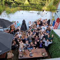 A group of about 50 people in an outdoor bar area smiling for a photo