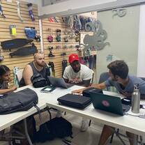 Team meeting indoors around a table with laptops and notes.