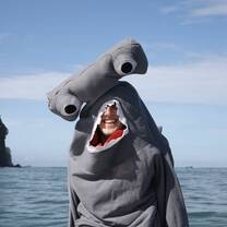 Intern wearing a hammerhead shark costume by the ocean.