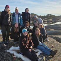 a group of college students pose together in an outdoor setting with hats and coats on in the chilly day