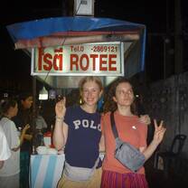 Two girls standing in front of a rotee street food cart 