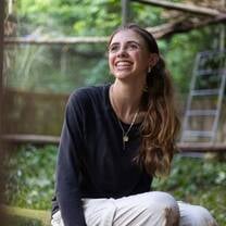 A young volunteer rests with a happy expression in the heart of the rainforest after a morning of hands-on conservation work.