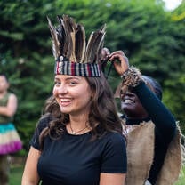 A local Tanzanian woman dressing a visitor in traditional ceremonial clothing and a handcrafted headband