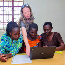 Volunteer reviewing health records on a laptop with local staff during program coordination at the Maisha center