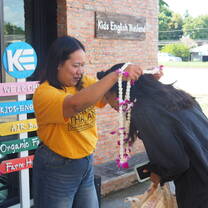 KET staff member welcoming a new arrival with a flower garland.