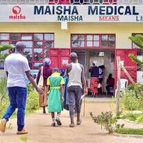 Community members and children walking into the Maisha Medical Clinic building in rural western Kenya