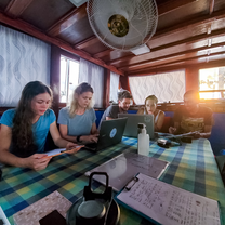 Volunteers entering data sat in saloon area of vessel