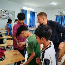 Teacher trainer providing individual mentoring and feedback to trainee at classroom desk.