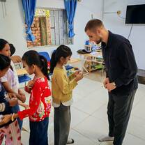 Students standing in line practicing English speaking activity with teacher guidance.