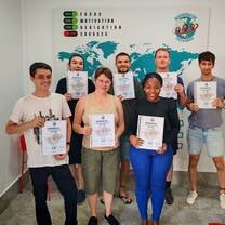 TEFL trainees holding certificates during graduation ceremony in training classroom.