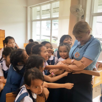 Jess in Thailand getting hugs from her young learners