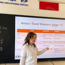 Female TEFL teacher pointing to interactive whiteboard at font of classroom
