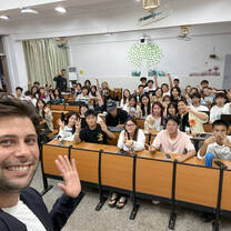 Smiling male TEFL teacher takes a selfie with a classroom full on students.