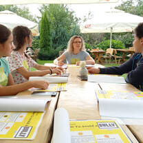Female TEFL teacher talking to students around an outdoor table.
