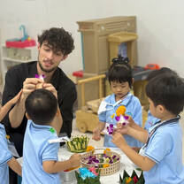 Young male teacher helps Asian students with their work.