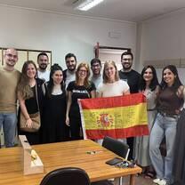 Group of male and female adults, one is holding a Spanish flag.