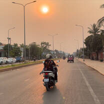 Motorcycle drives along a highway at sunset in Southeast Asia.