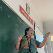 Female TEFL teacher in action wearing microphone and gesturing with hands.