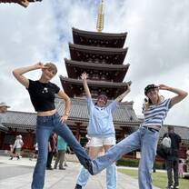 Three students posing dynamically in front of a tall section of Senso-Ji temple