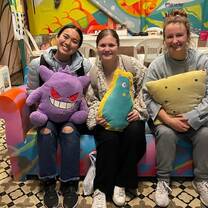 three girls holding stuffed animals on a couch