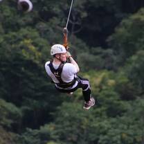 student ziplining through the forest
