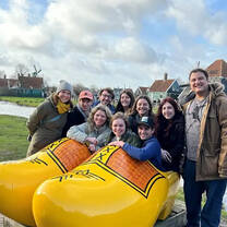 students in front of a giant yellow pair of clogs