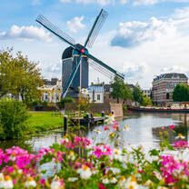 large windmill near a river with wildflowers